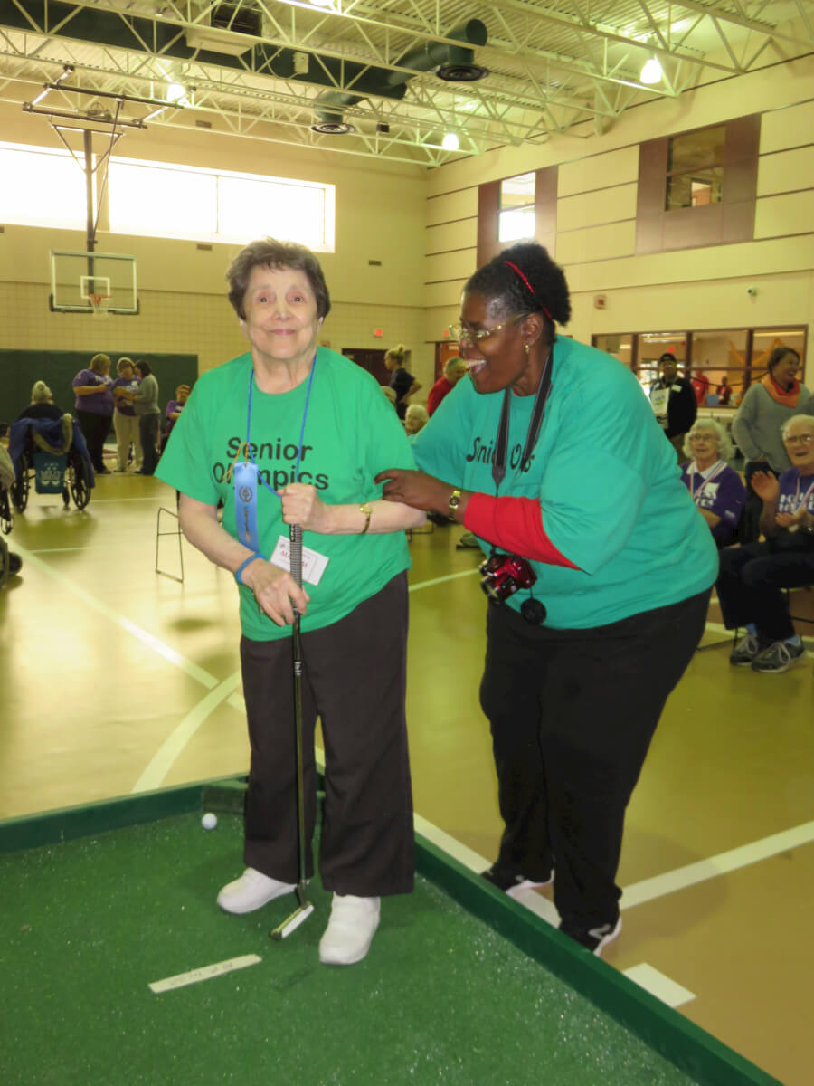 Mary Masceri participates in putt-putt golf with assistance from Toney