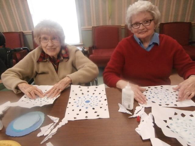 Twelve Oaks residents Marie Simpson and Brenda Edmonds create snowflakes for their craft project
