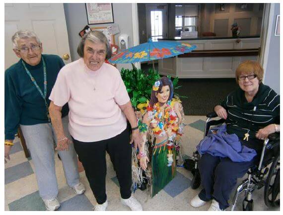 Glenwell residents Shirley Hanes, Sarah Kreigbaum and Janet Ruth show off the Hawaiian-themed float created by residents of Glenwell’s assisted living unit