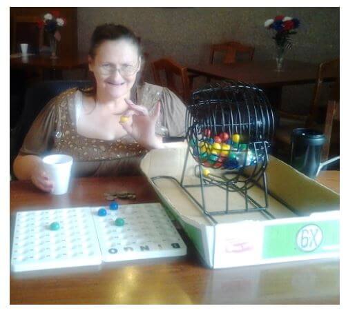 Heath House Resident Marsha Myers helps call bingo