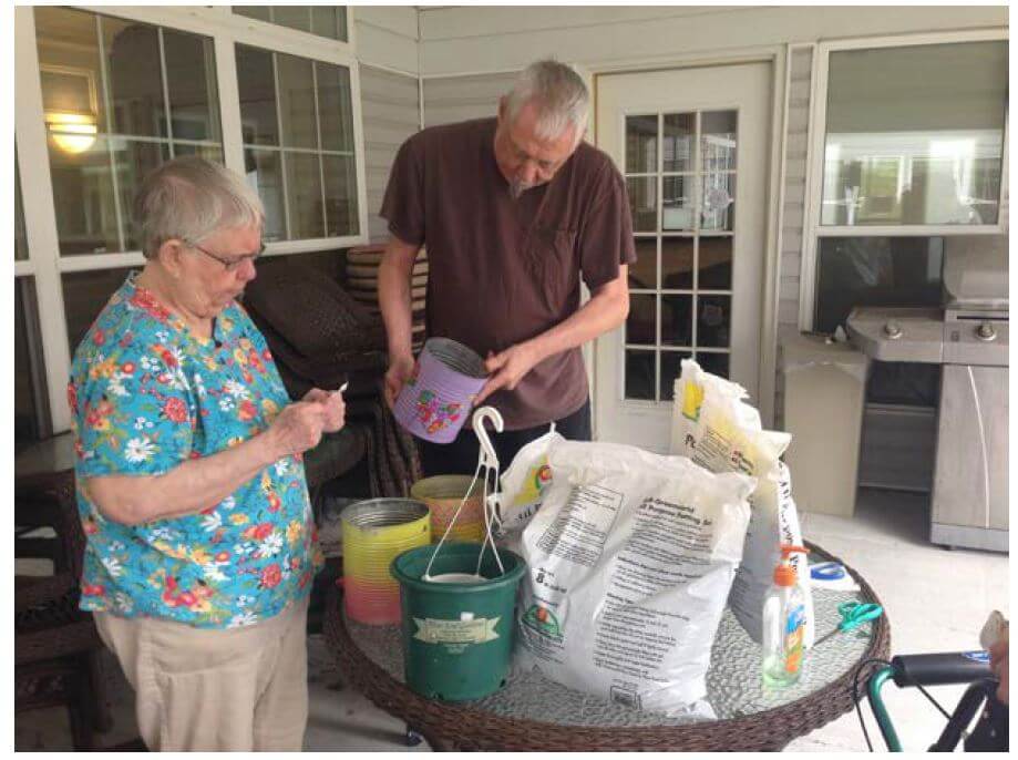 Woodcrest Commons residents Shirley Merton reads instructions on a seed packet while Bill Smith fills cans with dirt.