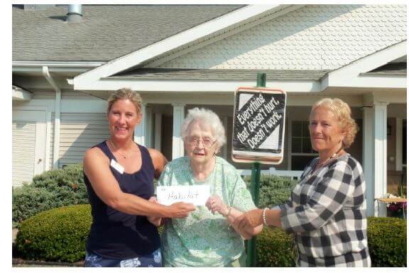 Flower City Habitat for Humanity Development and Communications Manager Teresa Bianchi accepts a check for $360 from Westwood Commons resident Jean Roda and Administrator Karen Shaffer.