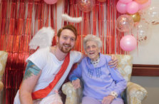 Senior woman posing next to man dressed as cupid with valentine's day decor