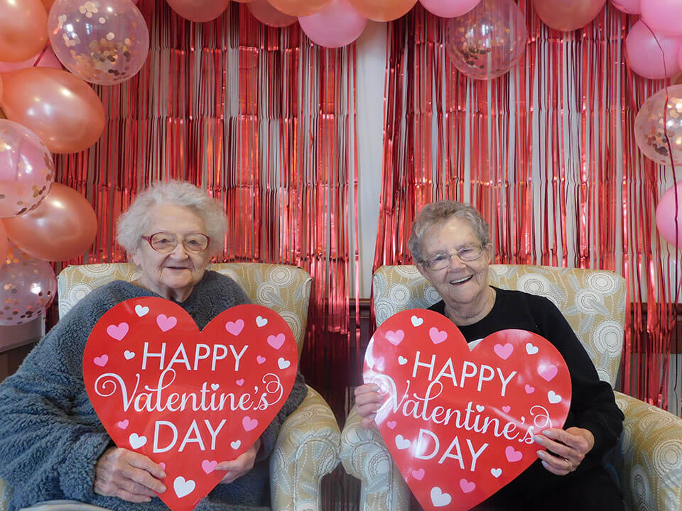 Two senior women posing with Valentine's Day decor