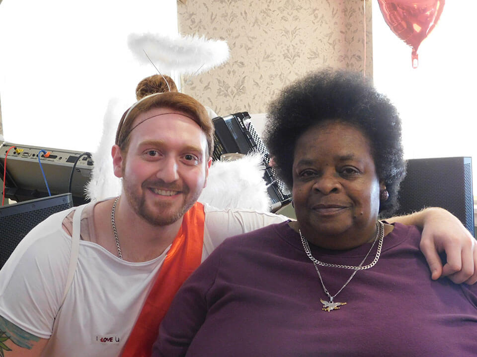 Senior woman posing next to man dressed as cupid with valentine's day decor