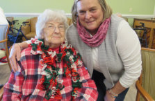 Elderly female resident receiving a hand knit scarf from a volunteer